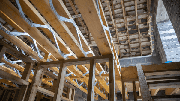Interior of a building project showing wooden stud walls and floor joists by by Henfaes from Getty Images and Canva